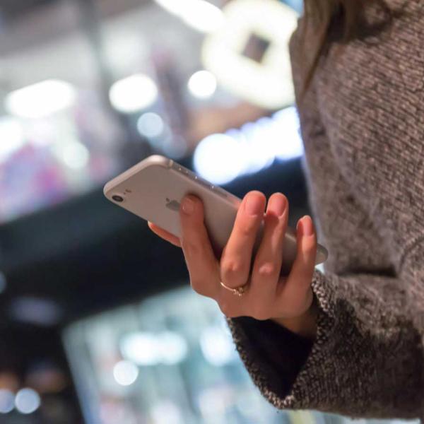 woman on a street at night looking at her mobile phone